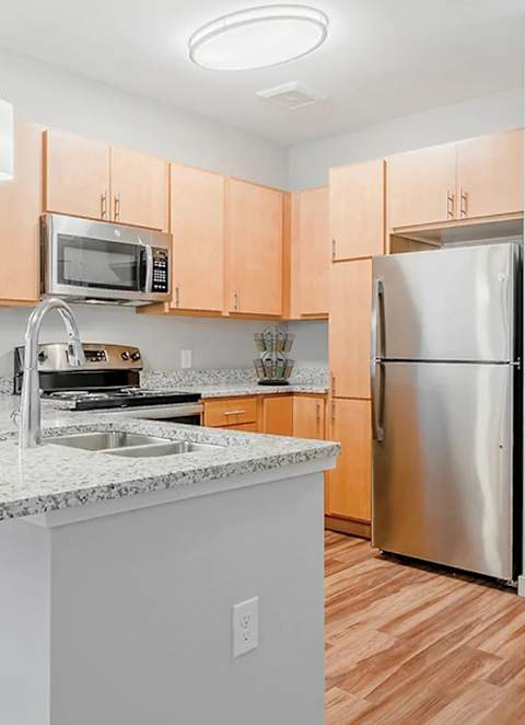 A kitchen with a white countertop and wooden cabinets is on the market.
