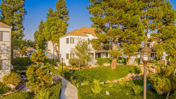 a garden with trees and a house in the background at Sendero Huntington Beach, Huntington Beach