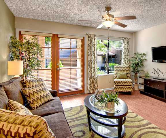 The living room with a couch, coffee table, decorations, a TV, and balcony at Desert Horizon. 