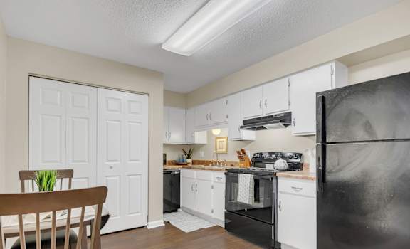 A kitchen with a black fridge and white cabinets.