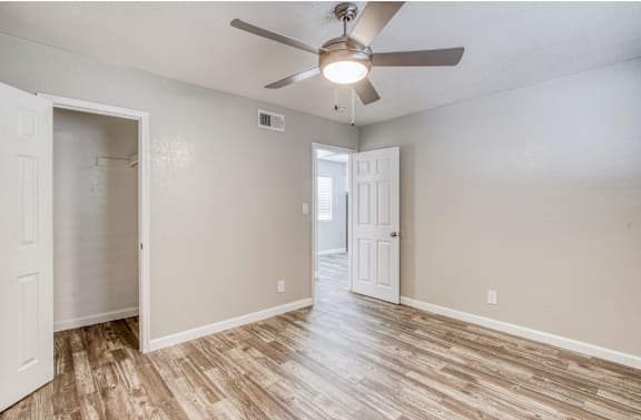 A room with a ceiling fan and light fixture, and wood flooring.