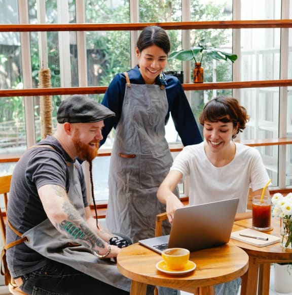 a group of people sitting around a table looking at a laptop