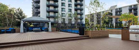 A wooden deck with a gazebo and a tall building in the background.