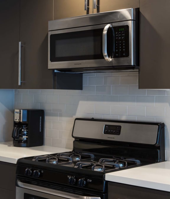 Kitchen with a stove top oven next to a microwave at 888 Hilgard – Furnished Apartments, Los Angeles