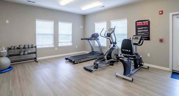 Gym with treadmills, elliptical machines, and a weight rack at Cedar Terrace Apartments in Hendersonville, 28792