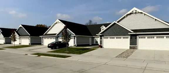A row of houses with a car parked in front of the first one.