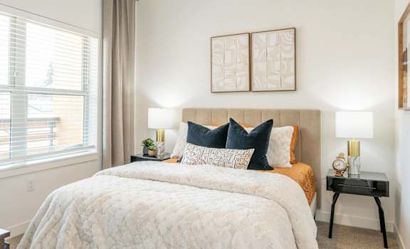 A bedroom with a large bed and two lamps.