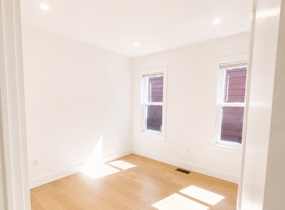 A room with wooden floors and two windows.