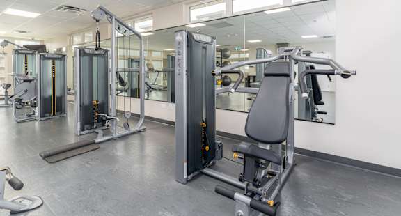 A gym with a variety of equipment including treadmills, stationary bikes, and weight machines. at G17 Apartments at Tamarack, Edmonton, AB