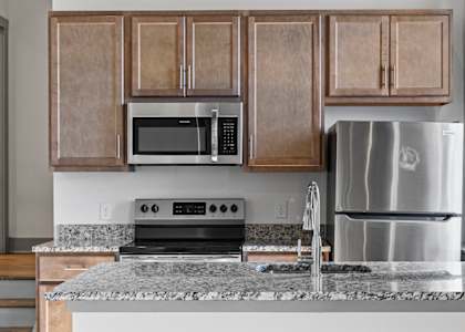 A kitchen with a stainless steel refrigerator, microwave, and oven.
