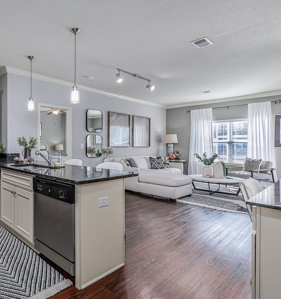 a kitchen with a large center island next to a living room with a couch and a coffee