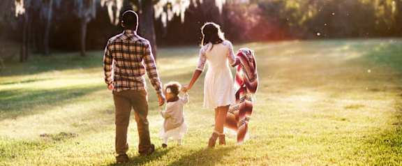 a family holding hands and walking through a field