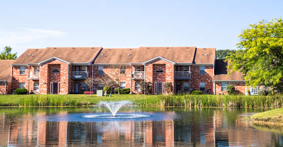 Lake view with fountain and trees at Bradford Run Apartments, 3604 Briarwick Dr, Kokomo