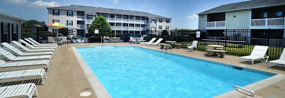A large swimming pool surrounded by sun loungers and chairs.