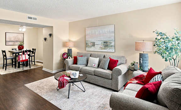 A living room with a grey couch, a coffee table, a dining table with chairs, and a painting on the wall.