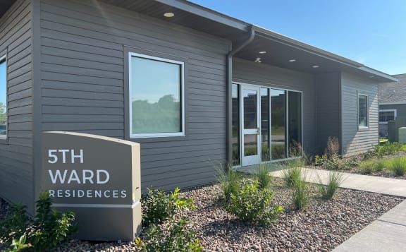 a gray building with a sign that reads 5th ward residences
