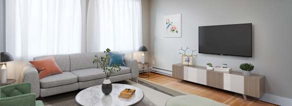 A living room with a grey sofa, a green armchair, a grey coffee table, a grey side table, a grey cabinet, a grey rug, a grey floor, a grey wall, a grey ceiling, a grey floor,