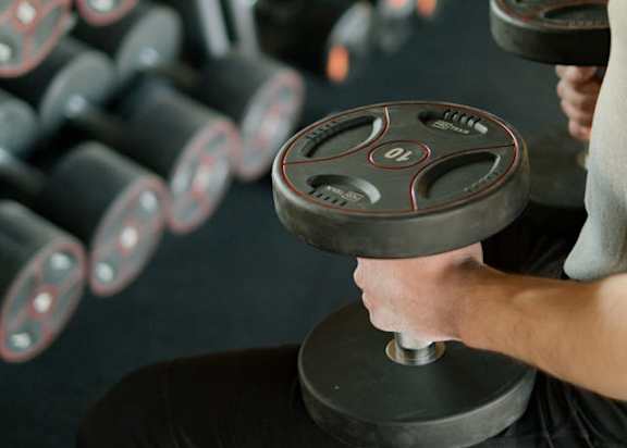 A man is lifting a dumbbell in a gym.