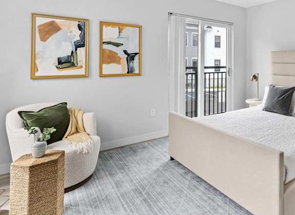 a bedroom with a bed and a chair and a door to a balcony