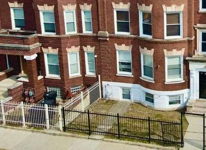 A red brick building with a black fence in front.