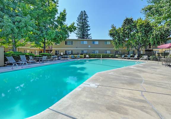 a swimming pool with trees and a building in the background