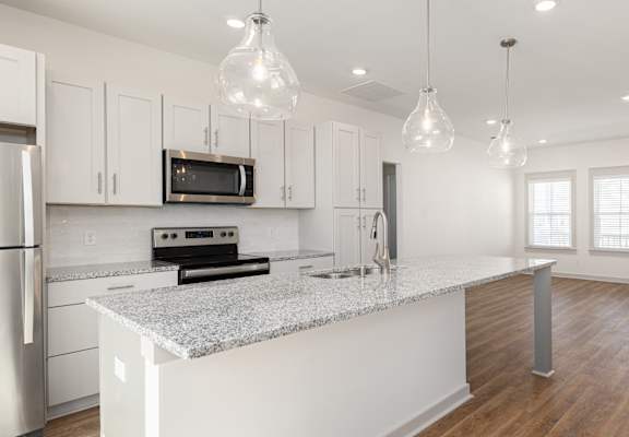 A modern kitchen with a granite countertop and stainless steel appliances.