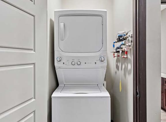 A white washing machine is in a small space between two doors.