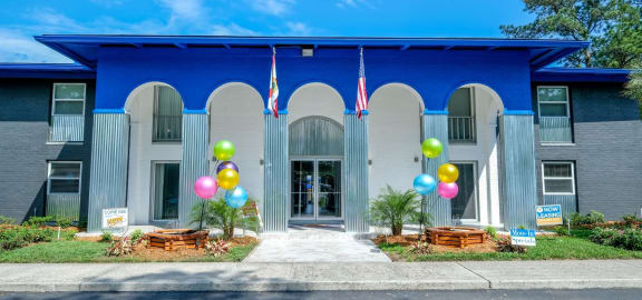 Jacksonville Mandarin Bay Apartments front office exterior. Front door is flanked by wood planters, colorful balloons, and the Florida and United States flags.