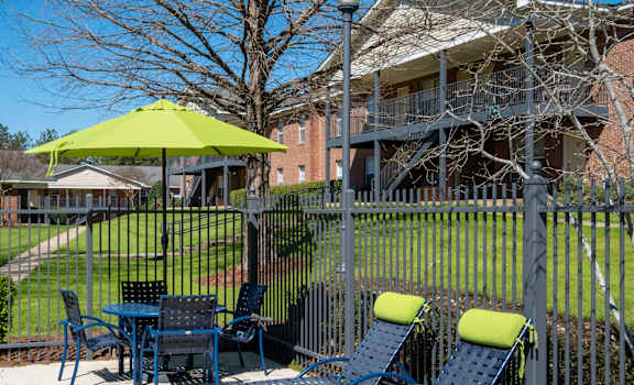 A patio with a table and chairs and a green umbrella.
