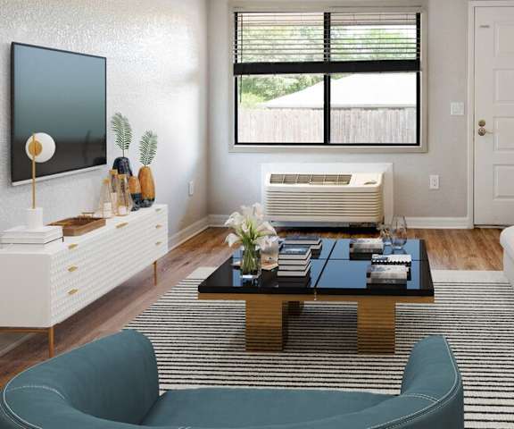 A living room with a white couch, a blue chair, a coffee table, and a television.