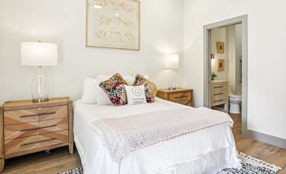 A bedroom with a white bed and a wooden nightstand.
