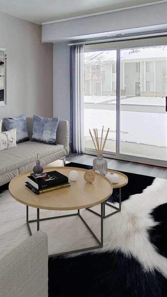 A living room with a grey couch and a painting on the wall.