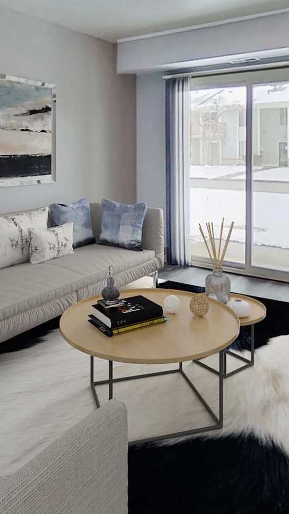 A living room with a grey couch and a painting on the wall.