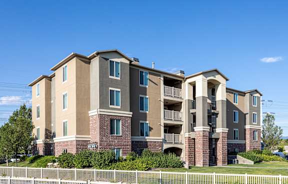 A large apartment building with a white fence in front.