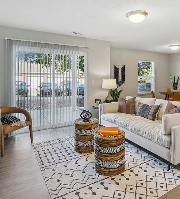 A living room with a white couch, a wooden cabinet, and a large mirror on the wall. at The Donovan Apartment Homes, Nebraska, 68516