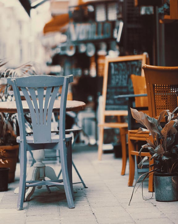 a patio with a blue chair and a table with a plant in front of it