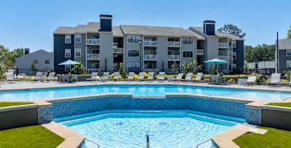 A large swimming pool in front of a multi-story apartment building.