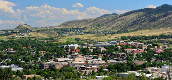 A cityscape with buildings and greenery under a blue sky with clouds.