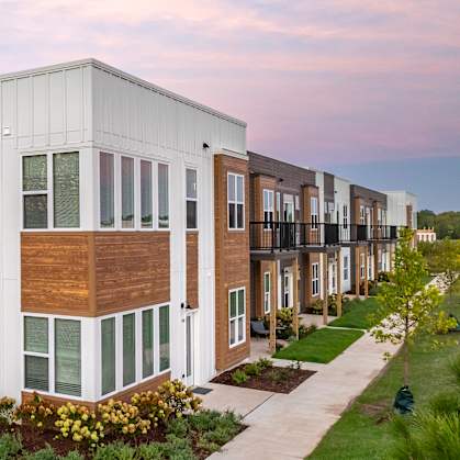 A modern apartment complex with a landscaped courtyard in front.