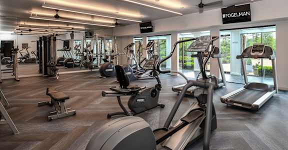 A gym with a variety of equipment including treadmills, weights, and exercise machines.