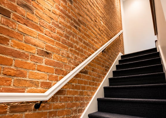 A staircase with a brick wall on one side.