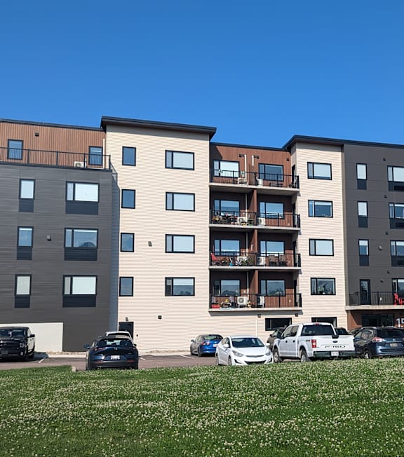 a view of an apartment building with cars parked in front of it