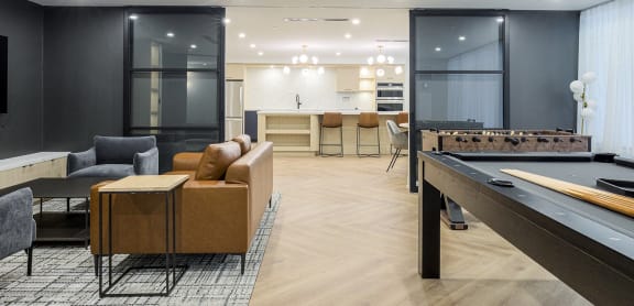 a living room with a pool table and a kitchen