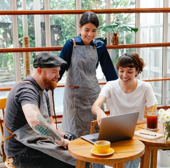 a group of people sitting around a table looking at a laptop