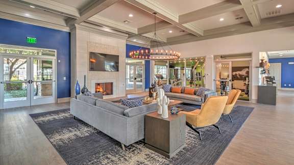 A spacious living room with a grey sofa set and a wooden floor.