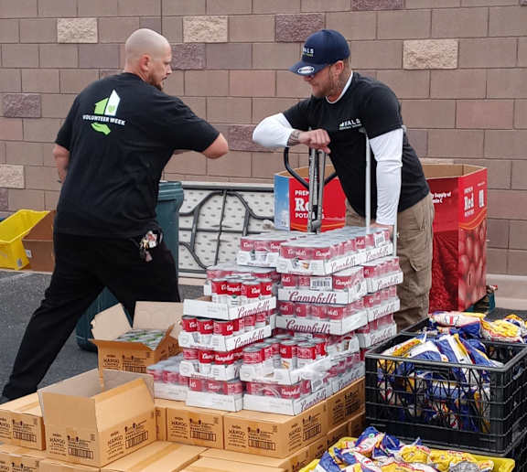 Two men in black shirts are working with boxes and bags of goods.
