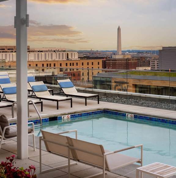 A pool area with chairs and a view of the Washington Monument.