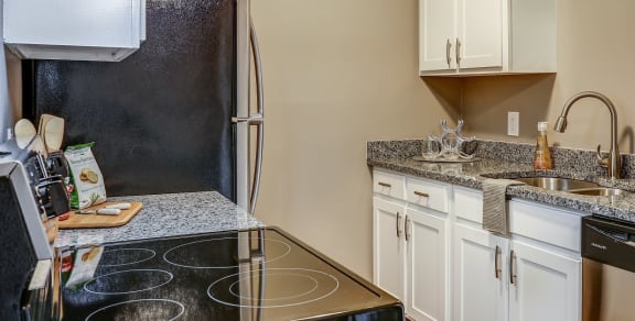 Kitchen with bright white cabinets, grey counter tops, stainless steal appliances, and tan walls.