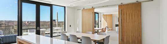 A modern dining room with a long table and chairs.