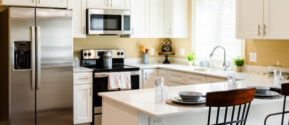a kitchen with white cabinets and a island with three chairs
